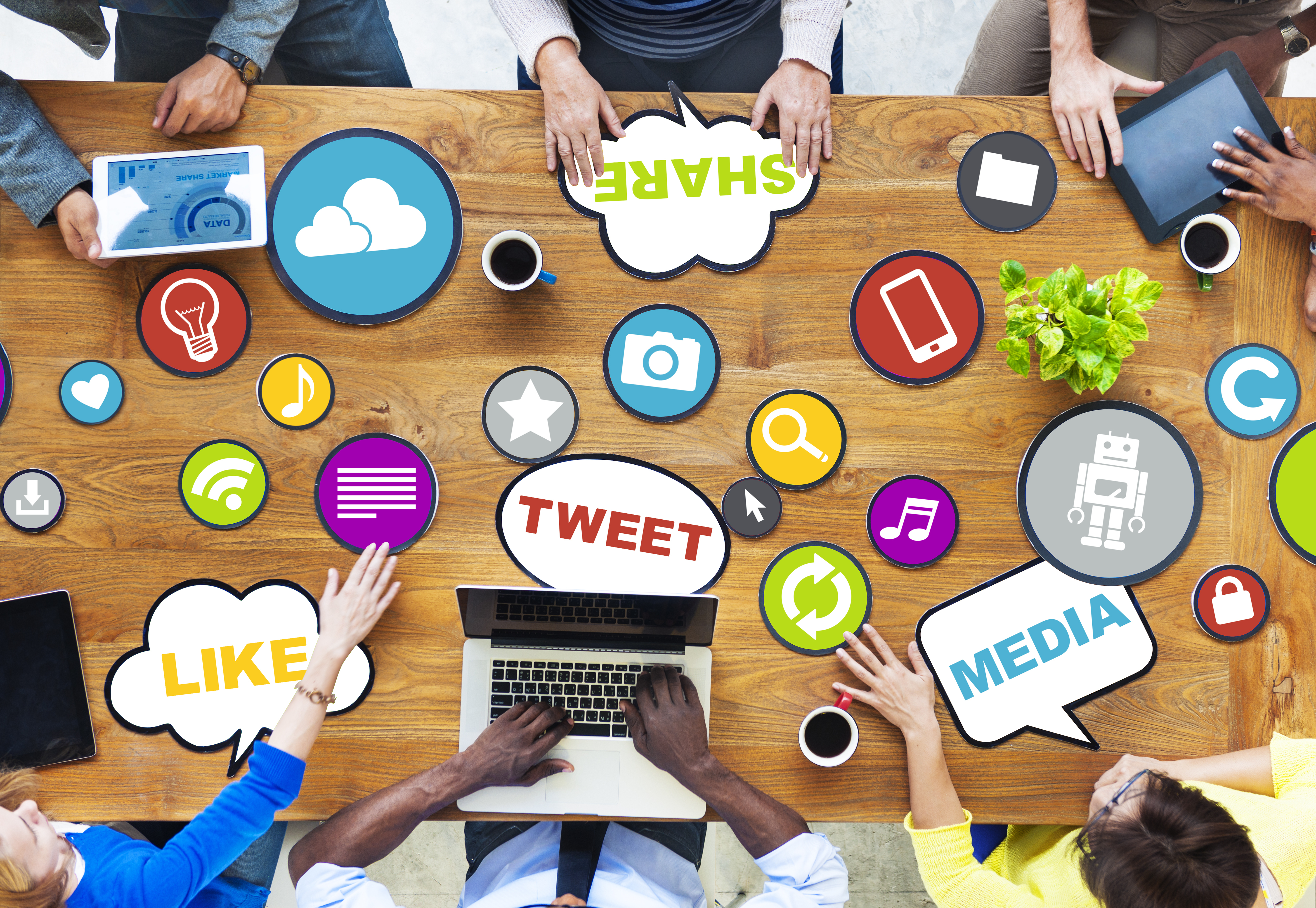 Workplace desk with various references to popular social media websites with workers sitting around it